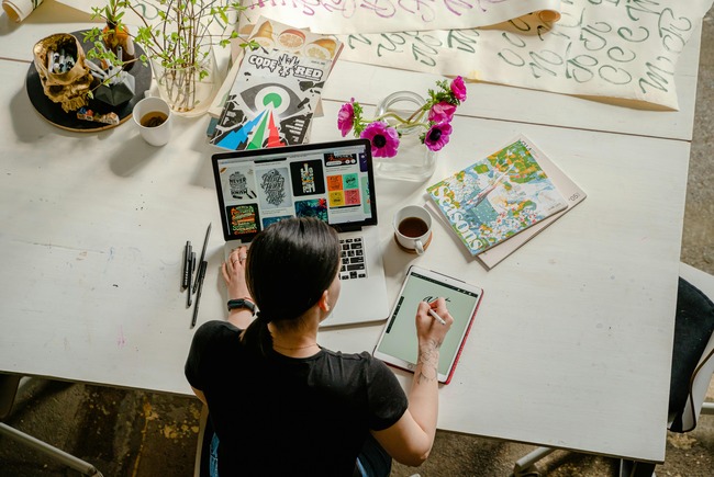 Woman designing a logo on tablet and laptop.