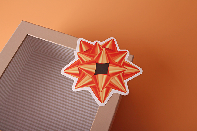 A neutral gift box decorated with a realistic metallic bow holiday vinyl sticker.