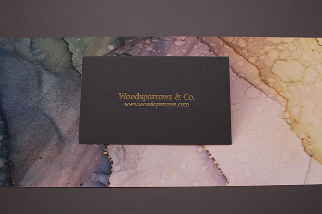 A dark textured business card featuring "Woodsparrows & Co." in an elegant gold serif typeface.