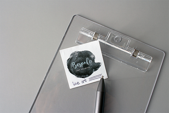 A square white paper sticker with a black watercolor logo.