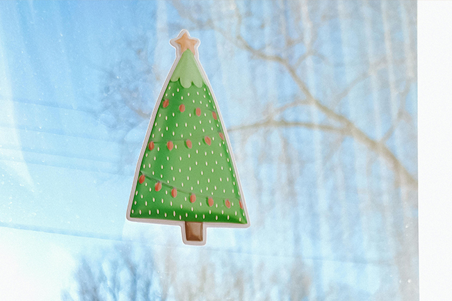 A green Christmas tree holiday vinyl sticker applied to a glass window.