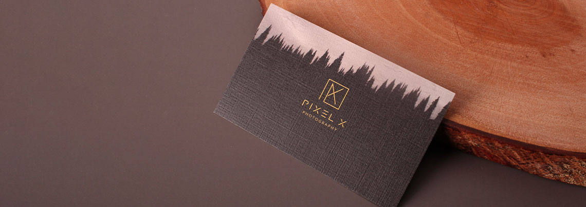 A textured black business card for a photographer featuring gold foil geometric typography and a tree silhouette
