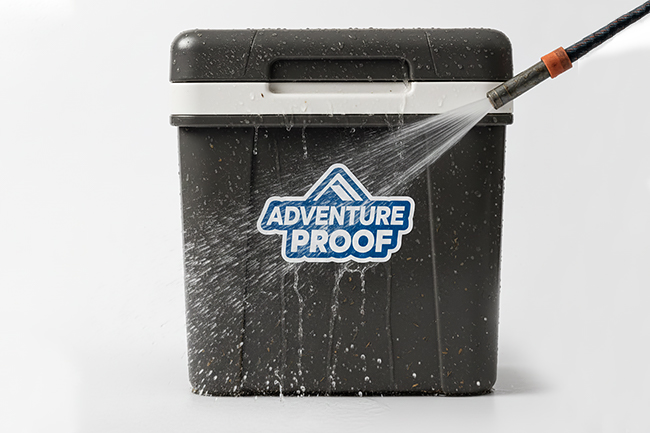 "Adventure Proof" sticker on a cooler being sprayed with a high-pressure water hose.