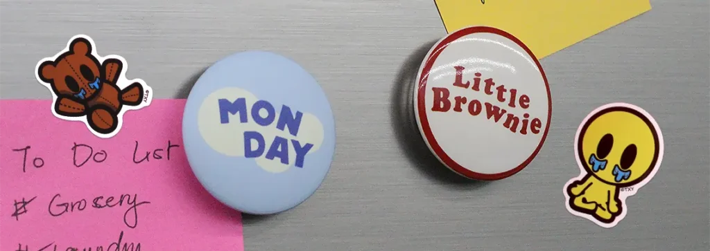 Die-cut stickers and round magnets used on a metal surface next to to-do lists.