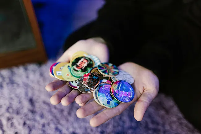 A person holding a handful of custom badges for events and brand promotion.