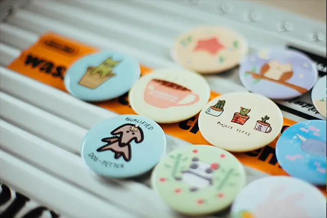 A row of minimalist custom badges for events featuring cute animal and coffee illustrations.