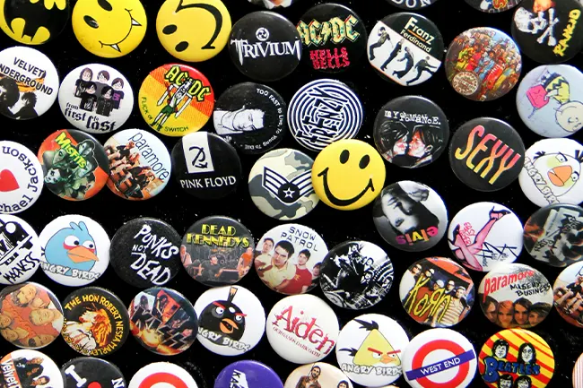A dense display of various pop culture badges featuring rock bands and iconic logos.