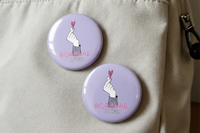 Two purple "Borahae" K-pop fan custom badges for events pinned to a white bag.