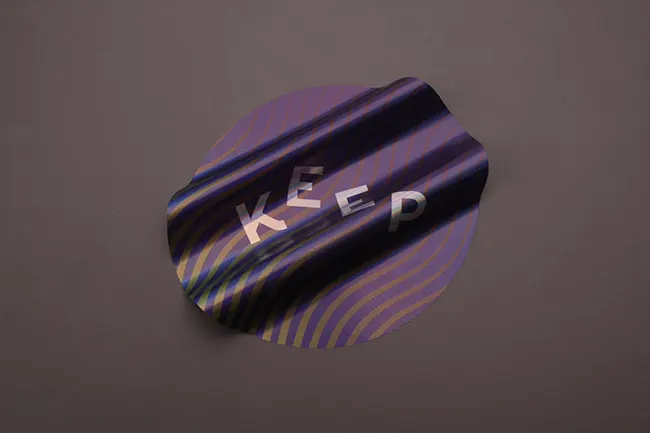 Iridescent holographic sticker with a wavy purple and gold reflective pattern.