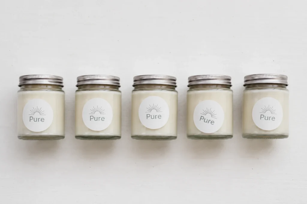 Five glass jars with round white Pure printed labels neatly arranged in a row on a white background.