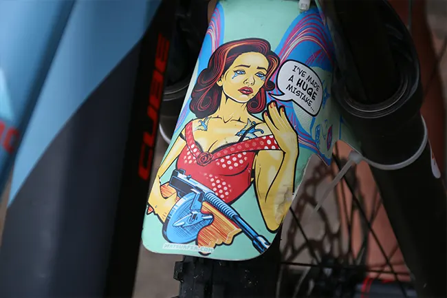 Pop Art style sticker on a bicycle mudguard featuring bold illustration, speech bubble text, and vivid flat colours