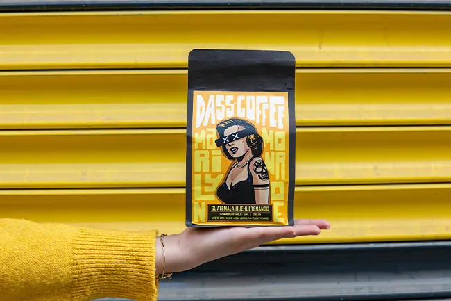 Independent coffee brand packaging with bold graphic figure and flat colour blocking on black