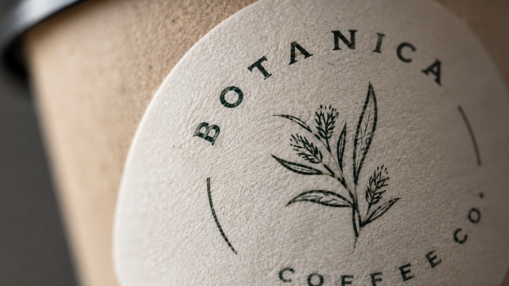 Close-up of a round textured paper sticker with a minimalist coffee cup design.